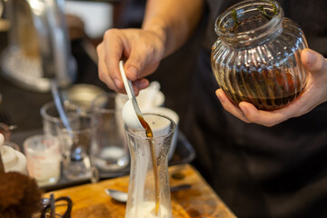 The bartender is using a white measuring spoon. Pour the honey into a glass with milk in the drink mix and design to add flavor to the drink.