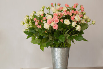 Bouquet of small pink and cream roses in a vase on the table
