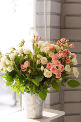 Bouquet of delicate pink and cream roses in a vase on the window