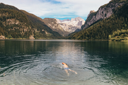 swimmer of European descent swims krauelm through the beautiful clear glacial lake Gosausee near the town of Gosau in northwestern Austria. Relaxing swimming overlooking the Austrian Alps