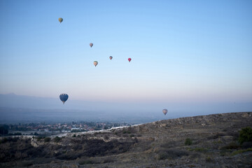 Multicolored hot air balloons flying in sunrise sky.