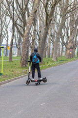 Young man on electric scooter with a second scooter for recharge working as juicer in urban city life style of eco friendly transportation and future mobility in hipster gadget zones as trendy motor