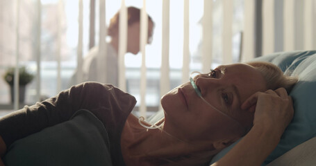 Sick aged woman with oxygen tube lying hospitalized in medical clinic.