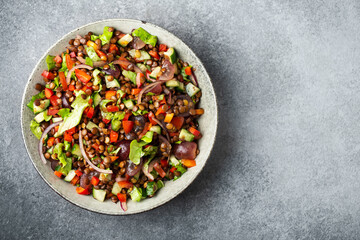 salad with lentils and vegetables in a deep plate on a dark gray background, vegetarian food, top view