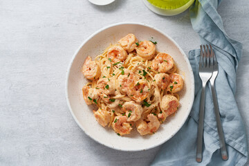 Pasta spaghetti with grilled shrimps bechamel sauce. Spaghetti with seafood rich cream. Cooking mediterranean food with savory prawns, macro top view, blue table, italian cuisine