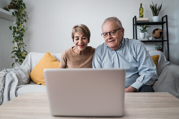 Happy senior couple doing video call at home - Main focus on woman face