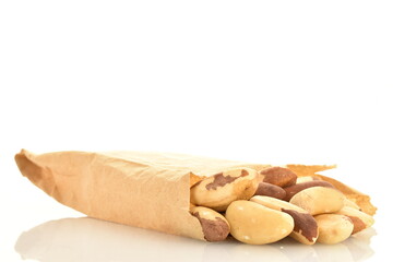 Several delicious organic Brazil nuts in a paper bag, close-up, isolated on white.