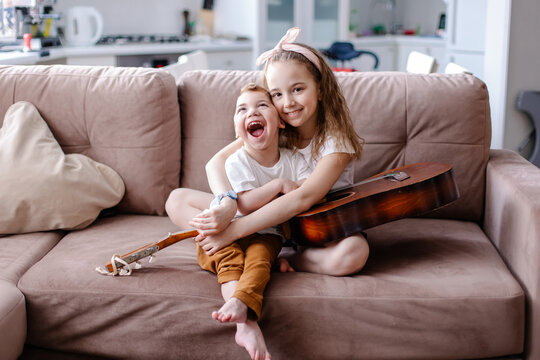 Sibling brother and sister play together. child with cerebral palsy with family in rehabilitation. Inclusion friendship with a disabled person. Music therapy playing the guitar. Happy kids laugh fun