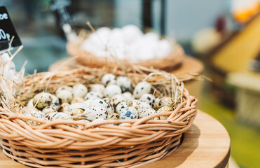 Quail eggs in bird nest on table background on farm market. Happy easter. Rustic style. Healthy, organic food.