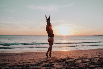 Fototapeta na wymiar Smiling young woman at sunset beach