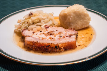 Slice of Austrian Roast Pork called Schweinsbraten with Coleslaw and Potato Dumpling on an Elegant Plate