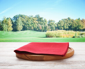 Pizza board, with napkin on wooden table and Summer landscape. Top view mockup