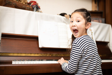 Fototapeta na wymiar ピアノを演奏しながらビックリしている少女