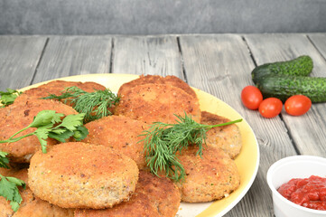 Fried cutlets arranged with herbs on a large white dish. Tomato sauce is nearby.