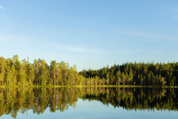 Fototapeta na wymiar Harmonious picture of a tranquil lake with reflections of trees and sky. Finland