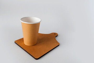 A disposable glass stands on a wooden board. Close-up.