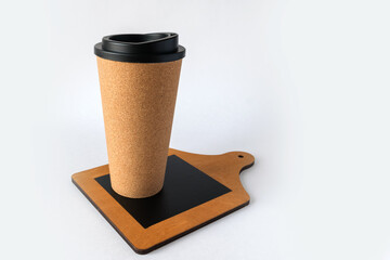 A tall cork glass with a lid stands on a wooden board. Close-up.