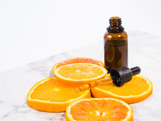 Vitamin C serum bottle with dropper on white marble background