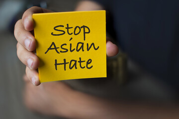 Hand holding a yellow Paper with the text : Stop Asian Hate