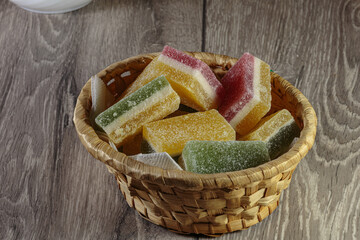 Multi colored layered marmalade in a wicker basket. Closeup of wonderful dessert.