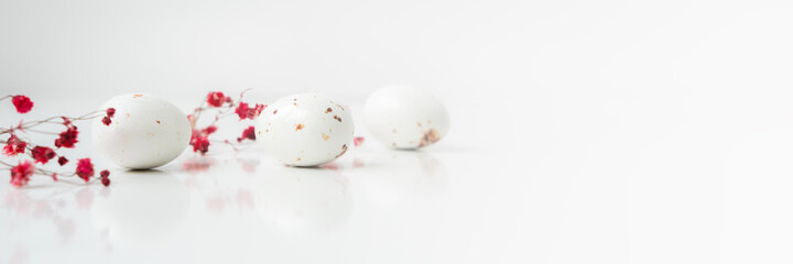 Easter minimal composition with eggs and flowers on the white background. Easter concept. Copy space. Banner.