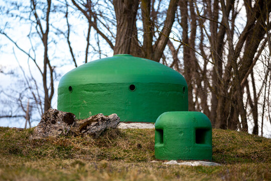 Green armored domes of bunkers sticking out of the ground, Pniewo, MRU. Picture taken on a cloudy day, soft shadows.