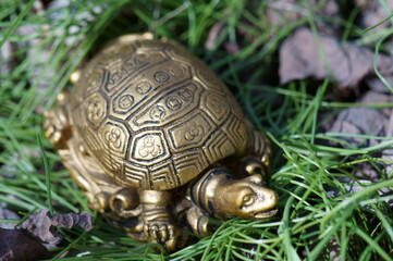 A turtle figurine in the green grass. A symbol of spring.