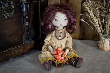 A textile interior doll sits against the background of a vintage chest. Handmade.
