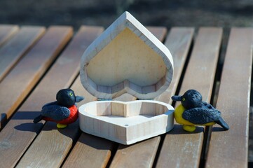 Two sparrows made of plasticine close-up. Between them is a wooden heart.