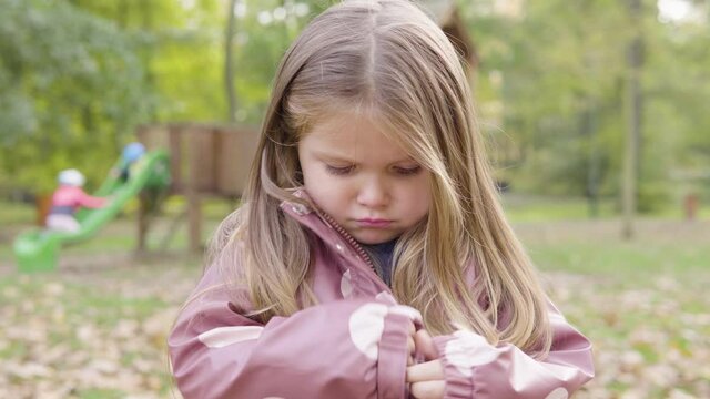 Cute little Caucasian girl is sad as her mom is angry at her at a playground - closeup