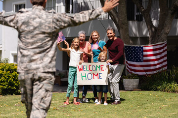 Caucasian soldier father and family meeting outside home with welcome sign and american flags