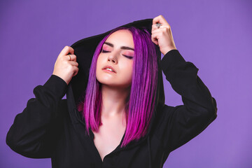 Model girl young beautiful stylish with hair dyed purple in a hood on a violet background