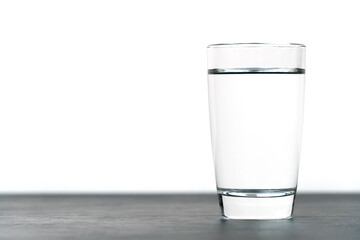 Close-up of a standing vodka glass on a black table on a white background with copy space. Macro