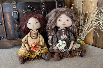 Two textile interior dolls sit against the background of a vintage chest. Handmade.