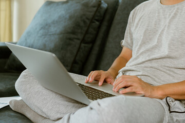 Naklejka premium Close up man hand using laptop for work during quarantine at home.