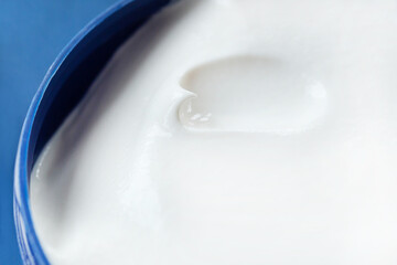 Face and body cream, white cream in a blue jar on a blue background