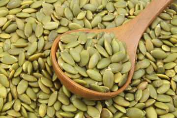 Green pumpkin seeds and wooden spoon