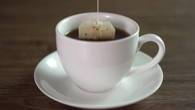 Tea bags in white ceramic mugs on wooden table, brew hot tea.