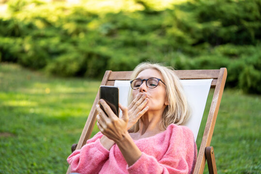 Smiling mature woman blowing a kiss while having video call on smartphone