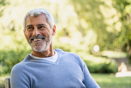 Smiling mature man sitting on chair in backyard