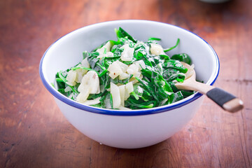 Spinach with garlic and onion in a white bowl