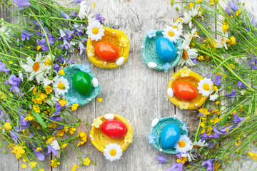 Fototapeta premium Colorful Easter eggs in the nests of wild wildflowers. Easter decoration in the country style. Horizontal background for Easter greetings. Copy space
