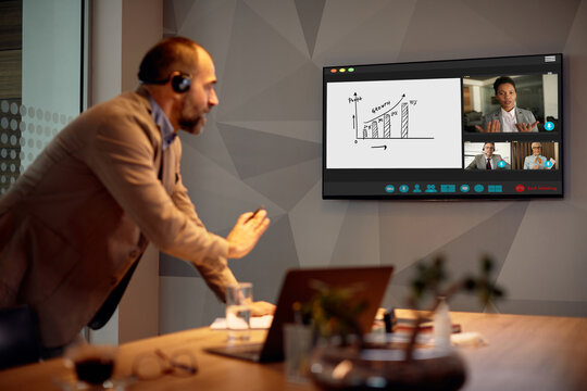 Business team discussing with executive manager about data graphs during online video conference.