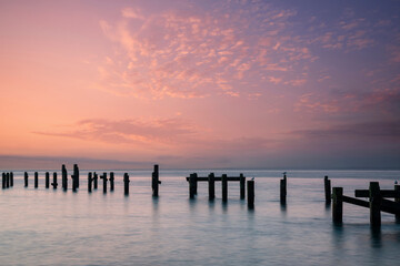 Stunning peaceful sea landscape of old derelict pier foundations at sunrise