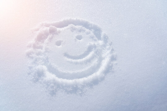 Drawing of a smiley in the snow, a ray of light. Top view