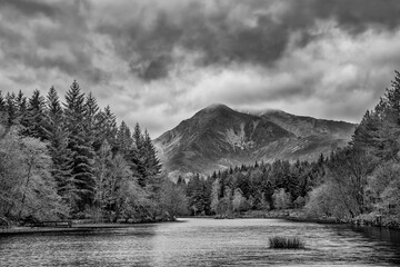 Stunning  black and white landscape image of Glencoe Lochan with Pap of Glencoe in the distance on a Winter's evening