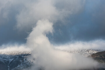 Epic landscape image of Skiddaw snow capped mountain range in Lake District in Winter with low level cloud around peaks viewed from Derwentwater