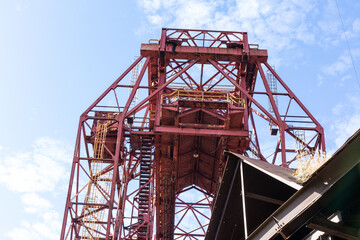 Open girders, ladders, and stairs of an abandoned industrial site against blue sky, horizontal aspect