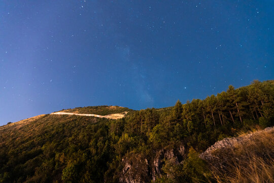 Low angle view of starry sky over tree covered mountain, Canyon Matka, Skopje, North Macedonia