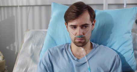 Depressed sick man sitting in hospital bed